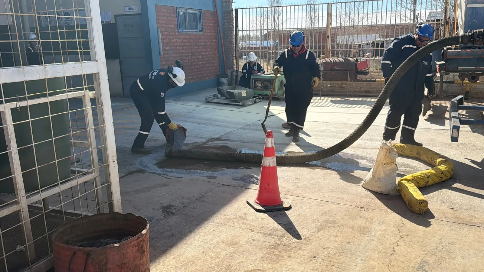 Operarios y mangueras en un espacio exterior de trabajo.