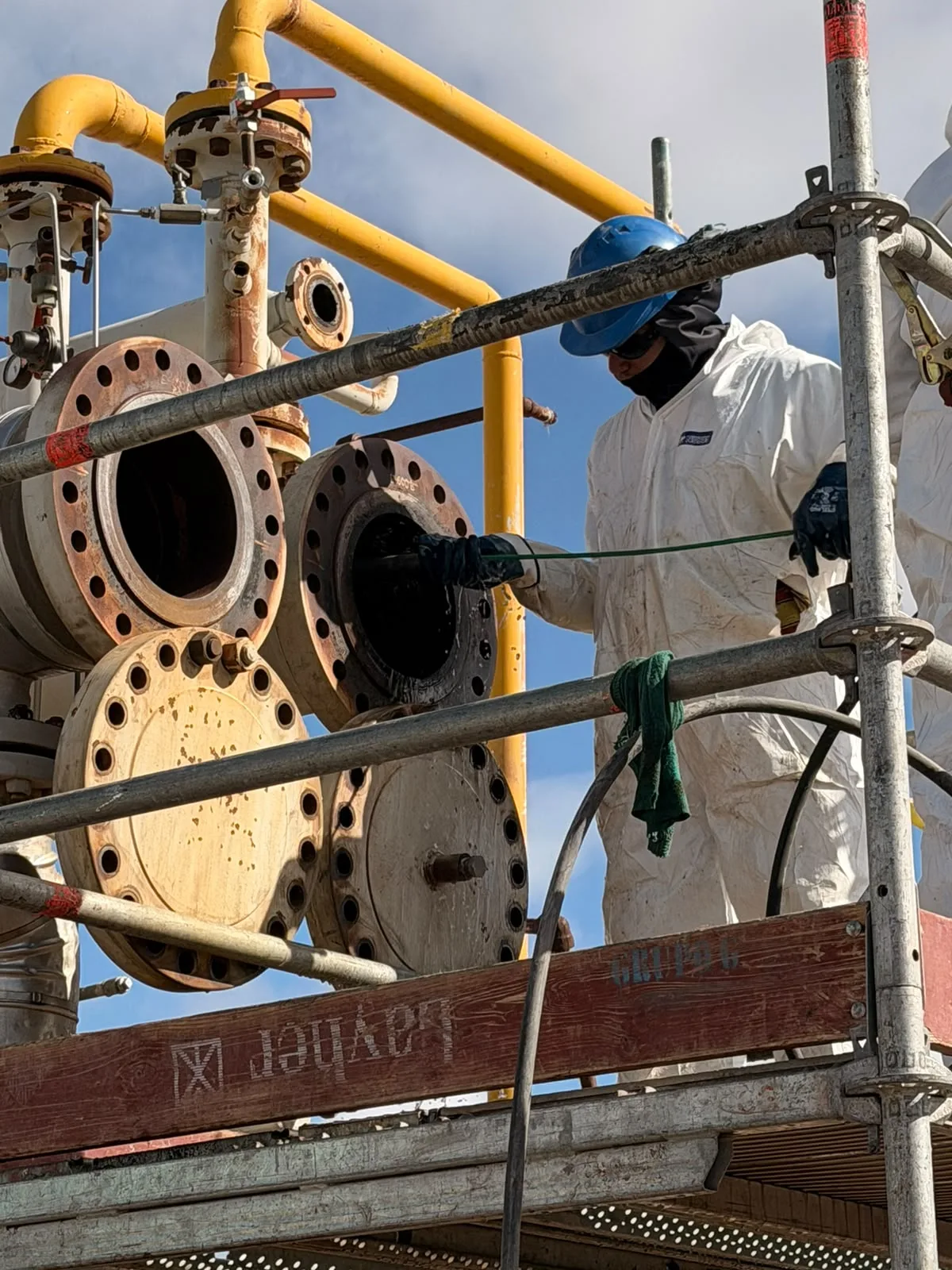 Personal trabajando junto a tuberías y una instalación industrial abierta.